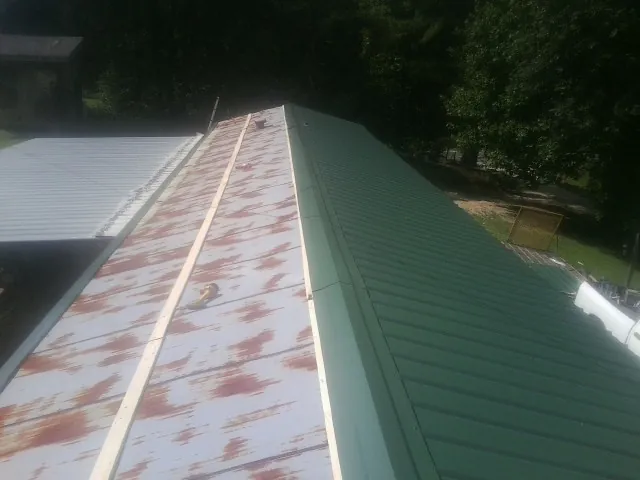 Old rusted panels beside newly installed green metal roofing — Wind Damage Roof Repair by Roofing Brothers in Delmont