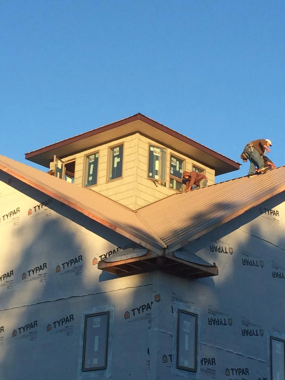 Roofers working around a rooftop cupola on a new metal roof at sunset — Roof Waterproofing in Delmont by Roofing Brothers
